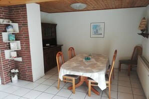A dining area with a table set for four, surrounded by wooden chairs. - Holiday home in Fehmarn with swimming pool (Fehmarn)
