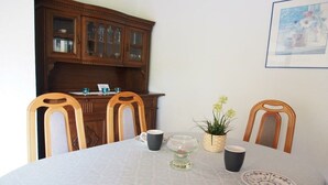 A dining table with chairs, a cabinet, and a framed picture on the wall. - Holiday home in Fehmarn with swimming pool (Fehmarn)