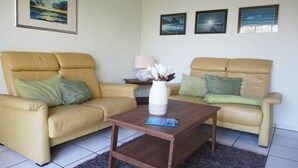 A living room with two beige sofas, a coffee table, and three framed pictures on the wall. - Holiday home in Fehmarn with swimming pool (Fehmarn)