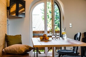 A dining area with a wooden table, a bowl of apples, glasses, and a bottle. - Holiday apartment with 1 bedroom (Garmisch-Partenkirchen)