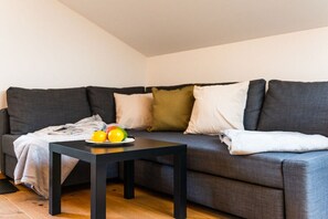 A modern living room with a grey sofa, a black coffee table, and a fruit plate. - Holiday apartment with 1 bedroom (Garmisch-Partenkirchen)