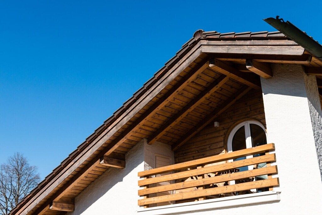 Een gebouw met een houten balkon en een helderblauwe lucht.