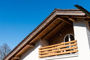 A building with a wooden balcony and a clear blue sky. - Holiday apartment with 1 bedroom (Garmisch-Partenkirchen)