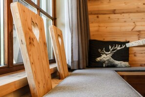 Een houten blokhut van binnen met een bankje en een kussen met een hertenprint.