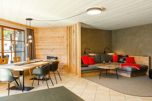 Un intérieur moderne avec un coin repas en bois, un ensemble de canapés et une petite table basse.