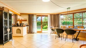 A spacious kitchen with a dining area, large windows, and a view of greenery outside. - Holiday apartment with 2 bedrooms (Farchant)