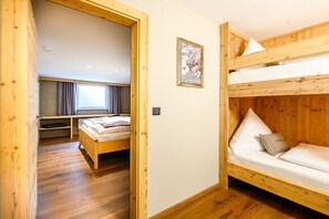 Ein Zimmer mit einem Etagenbett, einem Schreibtisch mit Stuhl und einem Fenster mit Vorhängen.