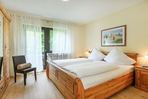 A bedroom with two wooden beds, a chair, a nightstand, and a painting on the wall. - Holiday apartment with 1 bedroom (Garmisch-Partenkirchen)