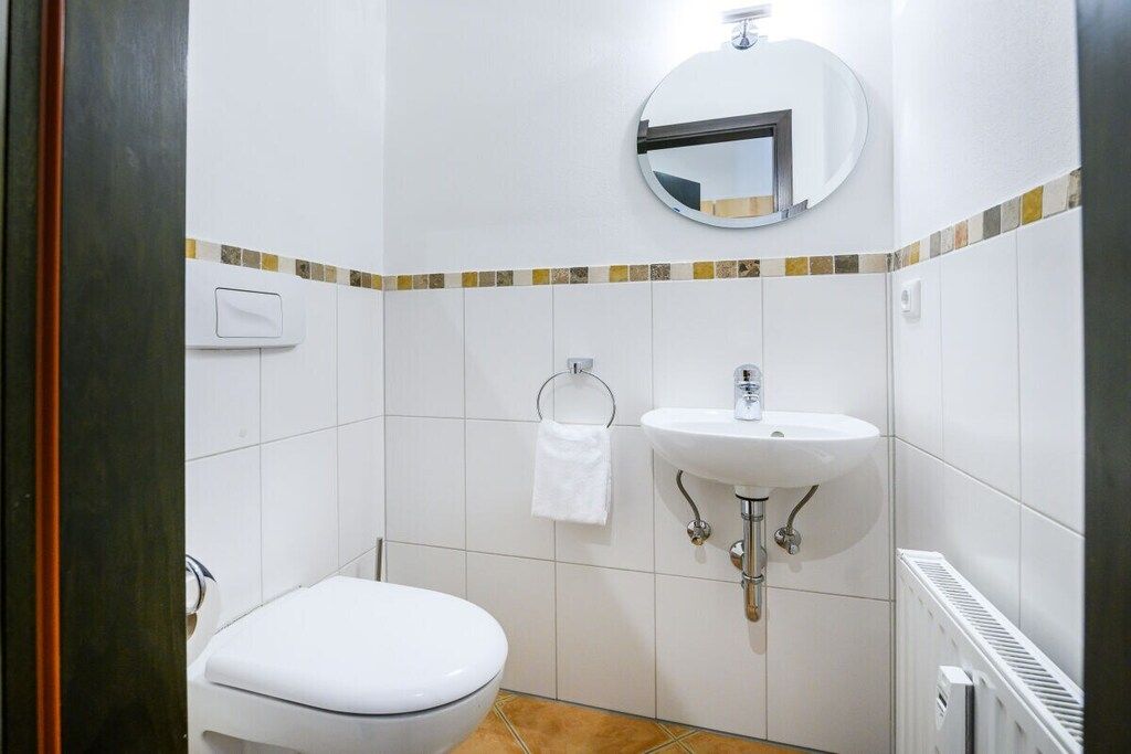 Un baño con inodoro, lavamanos, toallero y espejo.