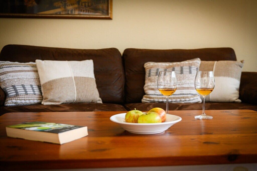 Une table en bois avec un livre, une assiette de pommes et deux verres de vin.