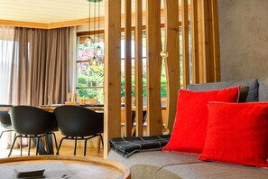 A modern living room with a sofa, red cushions, and a dining area with chairs and a table. - Holiday apartment with 1 bedroom (Farchant)