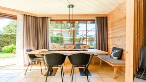 Un comedor con mesa de madera, sillas negras y un banco con cojines.