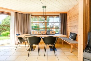 Een eetgedeelte met een houten tafel, zwarte stoelen en een bank met kussens.