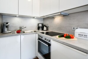 A modern kitchen with white cabinets, a built-in oven, a coffee maker, and a bread box. - Holiday apartment with 1 bedroom (Garmisch-Partenkirchen)