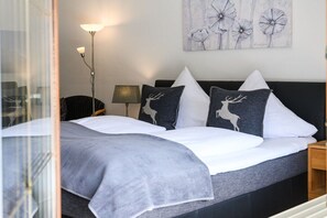 A bedroom with a bed, pillows, a lamp, and a wall art piece. - Holiday apartment with 1 bedroom (Garmisch-Partenkirchen)