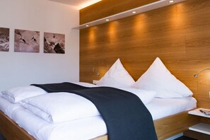 A modern hotel room with a wooden headboard, a bed with white bedding, and three framed photographs on the wall. - Holiday apartment with 2 bedrooms (Garmisch-Partenkirchen)