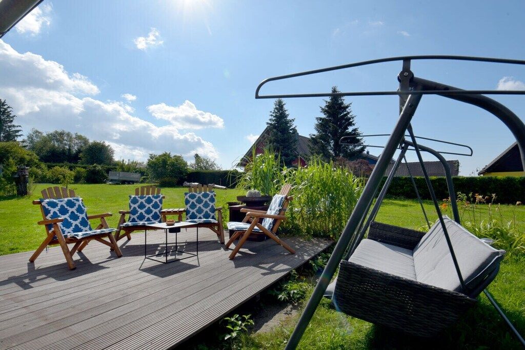 An outdoor deck with four Adirondack chairs and a swing chair.