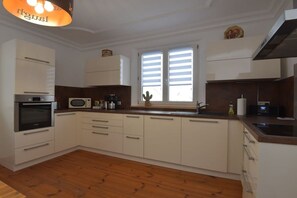 A kitchen with white cabinets, a microwave, a sink, and a wooden floor. - Holiday apartment with 3 bedrooms (Föritztal)
