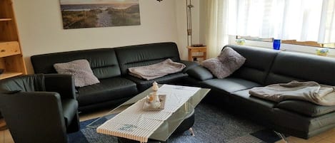 Una sala de estar moderna con un sofá de cuero negro, una mesa de centro de vidrio y una alfombra azul.