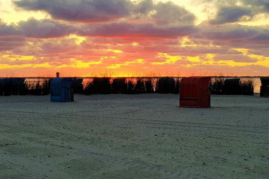 Eine offene Landschaft mit Sonnenuntergang im Hintergrund, eine blaue Struktur und eine rote Struktur.