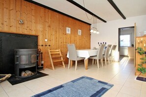 Ein Zimmer mit Kamin, einem Esstisch mit Stühlen und einer Holzwand.