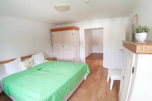 Et soveværelse med seng, garderobeskab, skrivebord og en potteplante.
