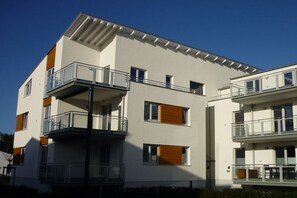 En moderne, høj beboelsesejendom med altaner og store vinduer.