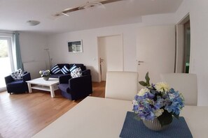 En stue med sofaarrangement, sofabord og en vase med blomster.