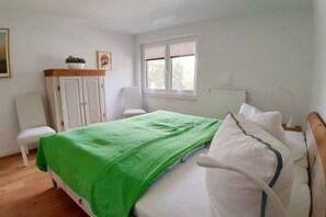 A bedroom with a bed, a chair, a wardrobe, and a window. - Holiday apartment with 2 bedrooms (Breege\/Juliusruh OT Juliusruh)
