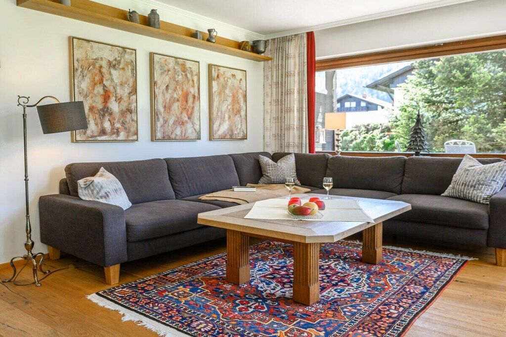 A modern living room with a sectional sofa, a coffee table, and a patterned rug.