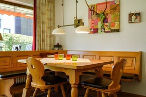 A dining area with a wooden table and chairs, a bench, and a decorative wall piece. - Holiday apartment with 2 bedrooms (Garmisch-Partenkirchen)