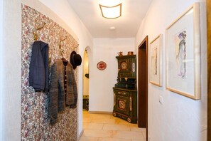 Ein Flur mit Wandpapier mit Muster, einem Kleiderständer, einer Uhr und gerahmten Kunstwerken.
