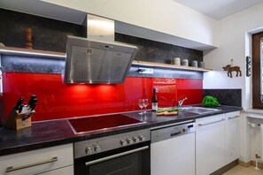Eine moderne Küche mit roter Spritzschutzwand, Edelstahlgeräten und einem eingebauten Backofen.