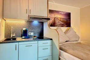 A compact kitchenette with a sink, a coffee maker, and a small bowl of fruit. - Holiday apartment with 1 bedroom (Kressbronn am Bodensee)