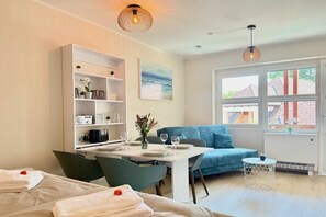 A modern hotel room with a dining area, a sofa, and a view of the outside. - Holiday apartment with 1 bedroom (Kressbronn am Bodensee)