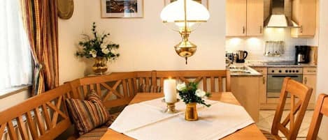 Un espace repas avec une table en bois, des bancs et un lustre.