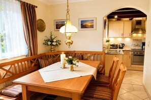 A dining area with a wooden table, benches, a candle, and a wall-mounted lamp. - Garden apartment 283 (Lübeck-Travemünde)