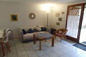 A living room with a sofa, a table, a chair, and a floor lamp. - Holiday home with 1 bedroom (Gruissan les Ayguades)