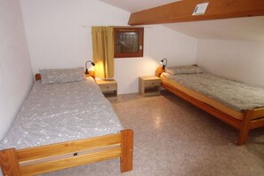A small, single-room accommodation with two wooden beds, each with a nightstand and a lamp. - Holiday home with 1 bedroom (Gruissan les Ayguades)