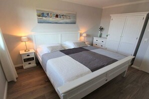 Ein Schlafzimmer mit einem Bett, Nachttischen, einem Kleiderschrank und einem Bild an der Wand.