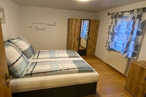 A bedroom with a bed, a wardrobe, a radiator, and a wall with a quote. - Holiday apartment in Langdorf with barbecue (Langdorf)