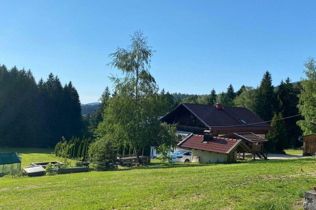 A rural house with a sloped roof, surrounded by a grassy area and trees.