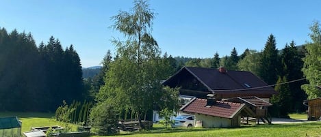 A rural house with a sloped roof, surrounded by a grassy area and trees.