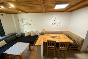 A cozy living area with a sofa, a wooden table, and a bench. There are wall decorations and a ceiling with wooden beams. - Holiday apartment in Langdorf with barbecue (Langdorf)
