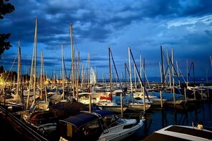 A marina with multiple boats docked, surrounded by calm water and a cloudy sky. - Holiday apartment with 1 bedroom (Friedrichshafen)