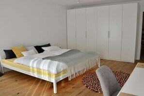 Una camera da letto con un letto, un armadio bianco e un tappeto rotondo.