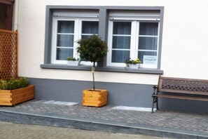 A building with two windows, a bench, and planters with plants. - Holiday apartment with 1 bedroom (Cochem)