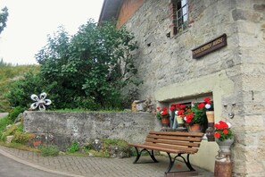 Ein Steinhaus mit einem Schild, auf dem 'BAIERNHOFF NUSE' steht, und einer Bank davor.