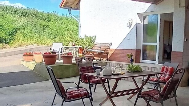 An outdoor patio with a table and chairs, potted plants, and a building with a white exterior and large windows. - Holiday apartment with 3 bedrooms (Marsberg)