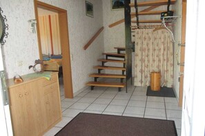 Ein Zimmer mit einer Holztreppe, einem Holzschrank und einer Tür zu einem anderen Raum.